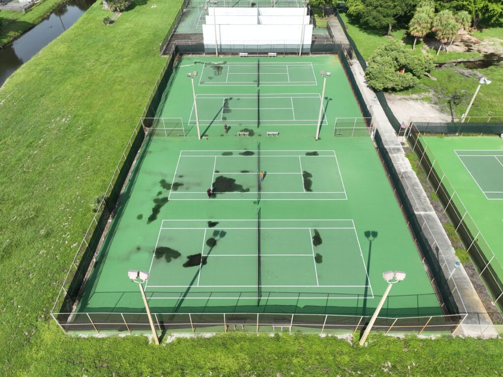 Aerial view of a tennis court with players actively engaged in games.