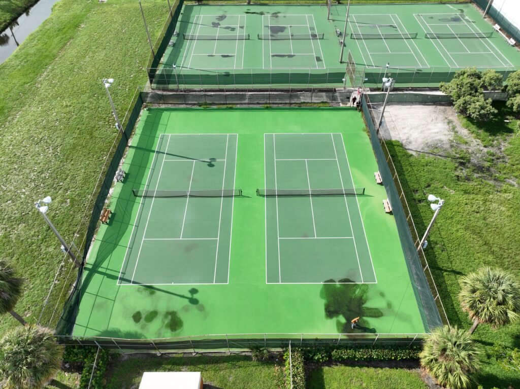 Aerial view of two adjacent tennis courts with green surfaces.