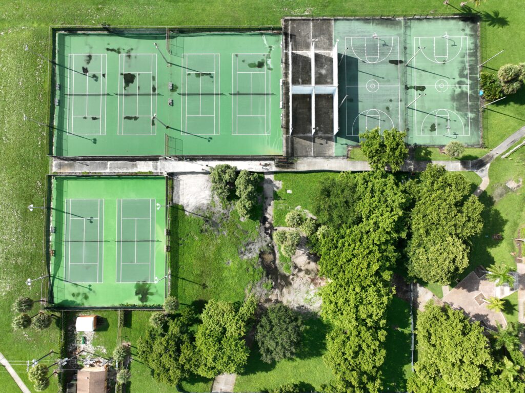 Aerial view of multiple tennis courts surrounded by greenery.