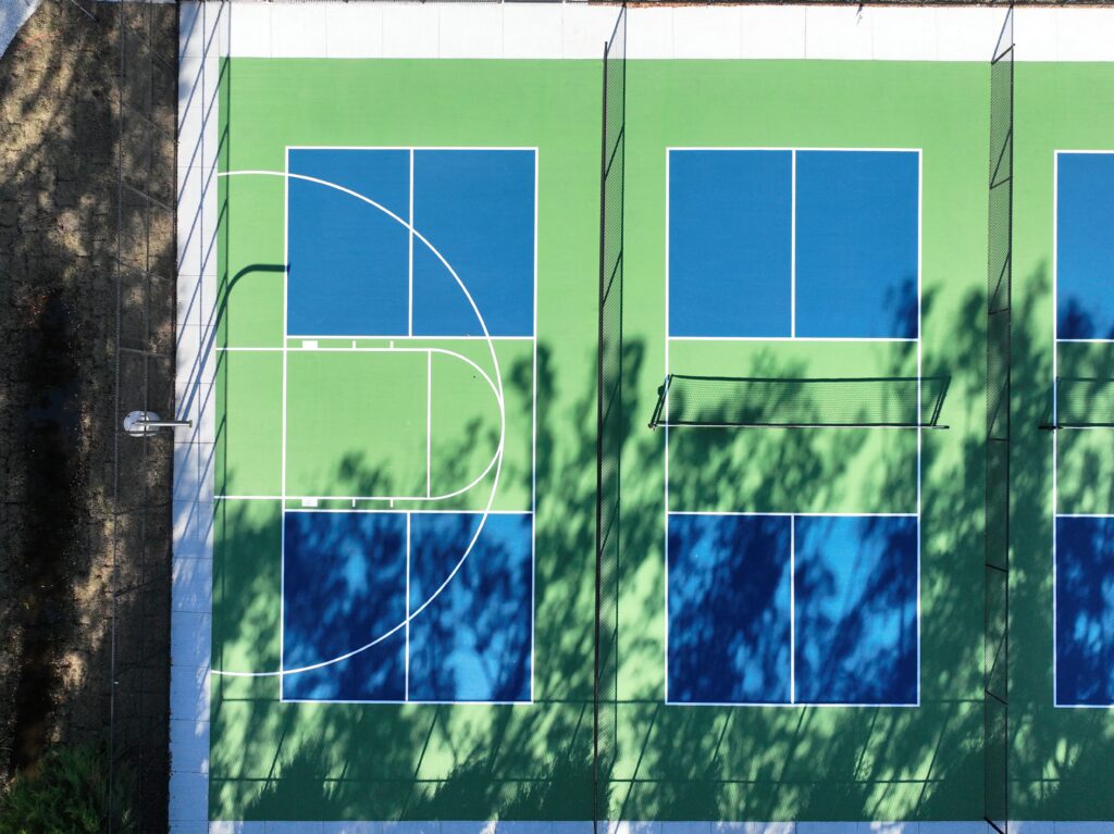 Green building facade with blue windows and tree shadows.