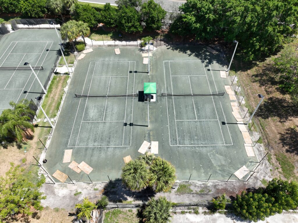 Aerial view of multiple outdoor tennis courts surrounded by trees.