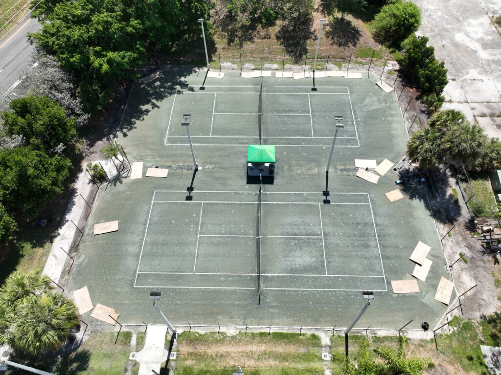 Aerial view of multiple tennis courts with nets and surrounding greenery.