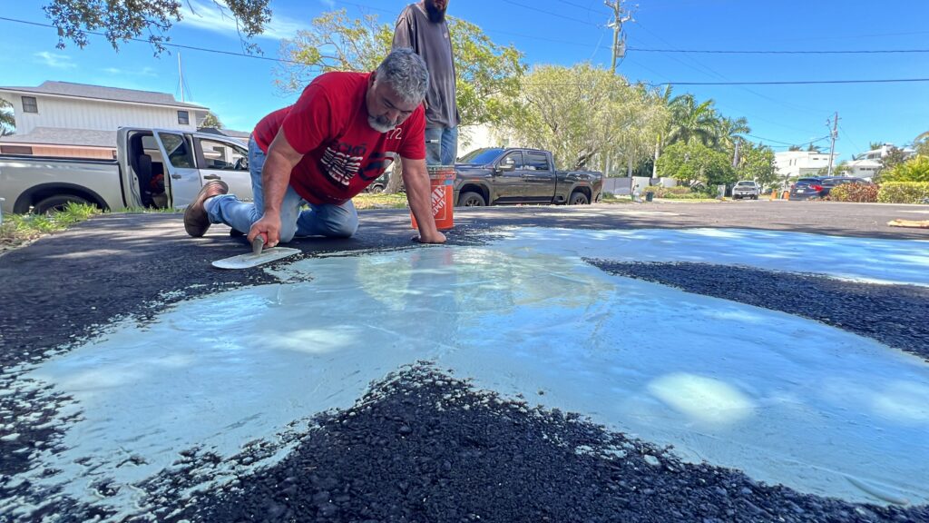 A person smoothing asphalt on a sunny day.