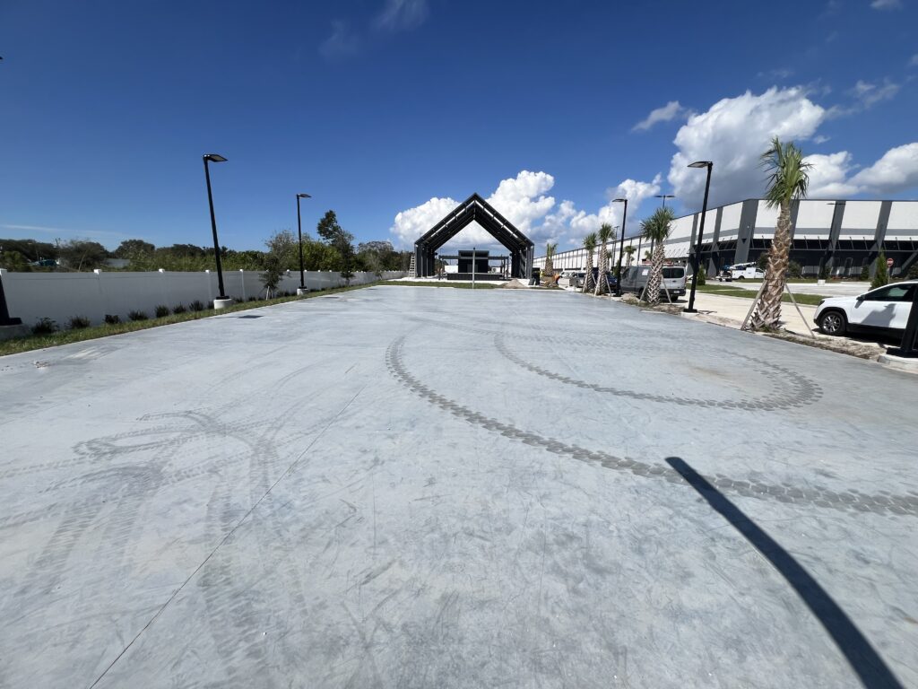 A newly paved concrete area near a river with a small pavilion and clear sky.