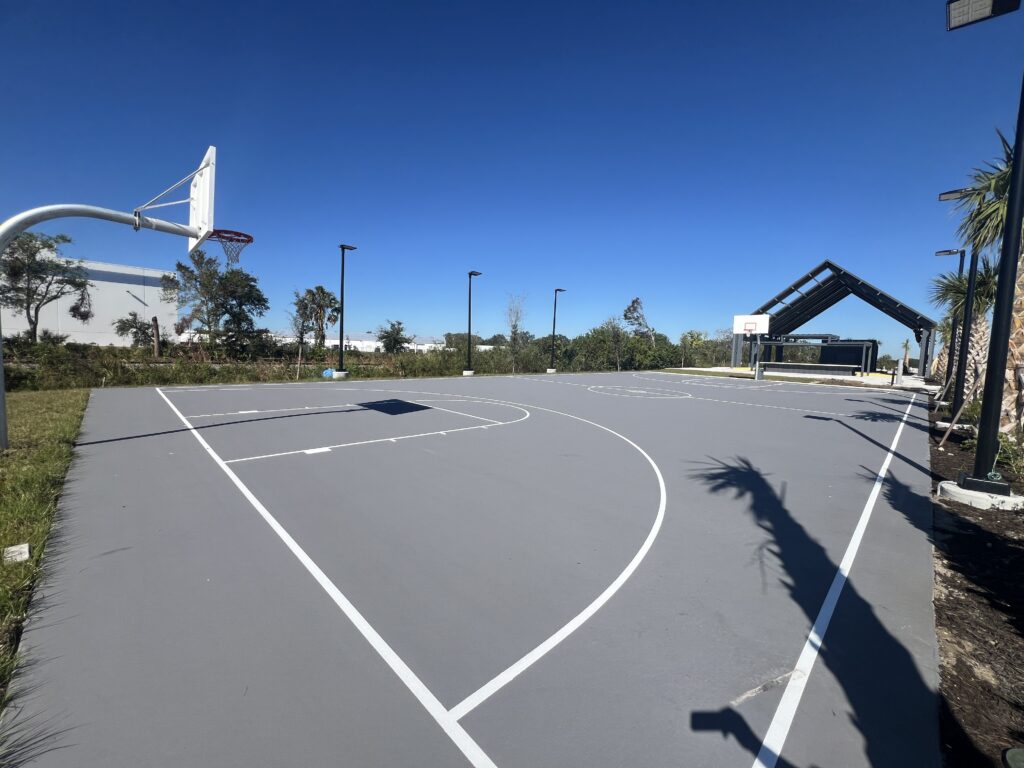 Empty outdoor basketball court on a sunny day with clear blue sky.