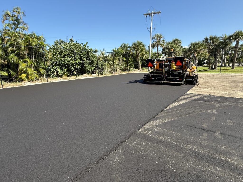 A road roller paving fresh asphalt on a sunny day.