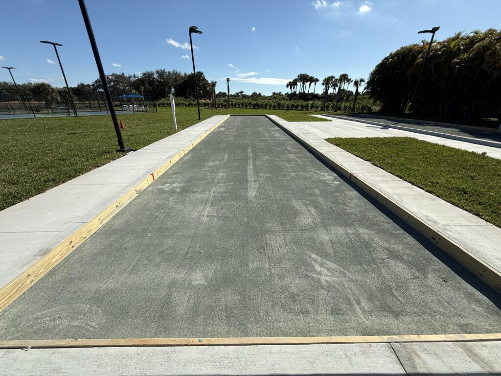 Newly paved concrete road under a clear blue sky.