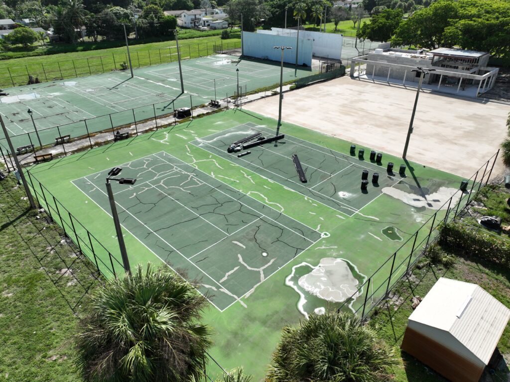 Outdoor sports courts with people playing tennis on a sunny day.