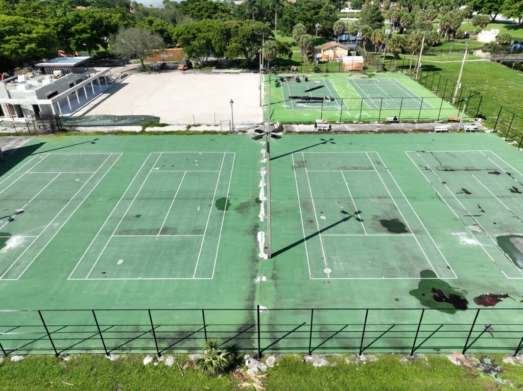 Multiple outdoor sports courts including tennis and basketball under sunlight.