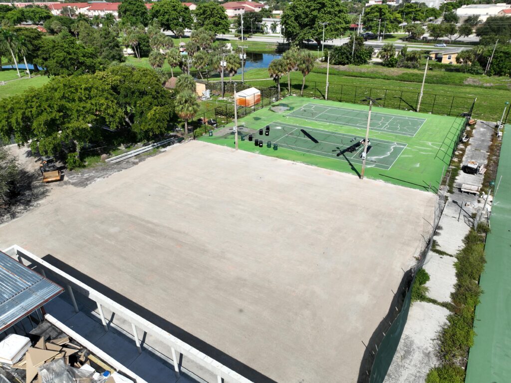 A rooftop basketball court next to a large empty roof area.